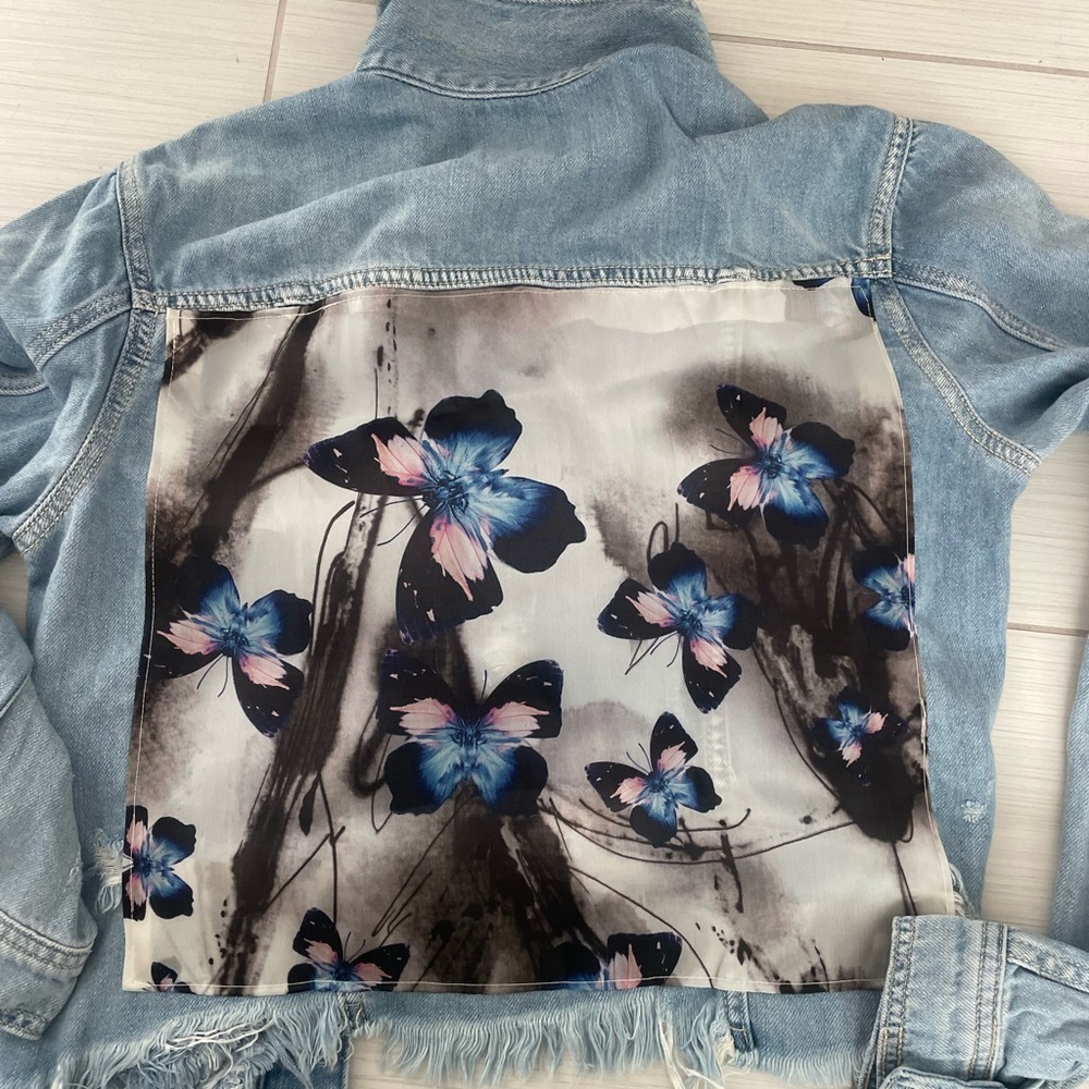Light denim jacket with butterfly scarf on the back. Size small.